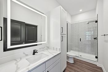 A modern bathroom with a white sink and a walk-in shower.